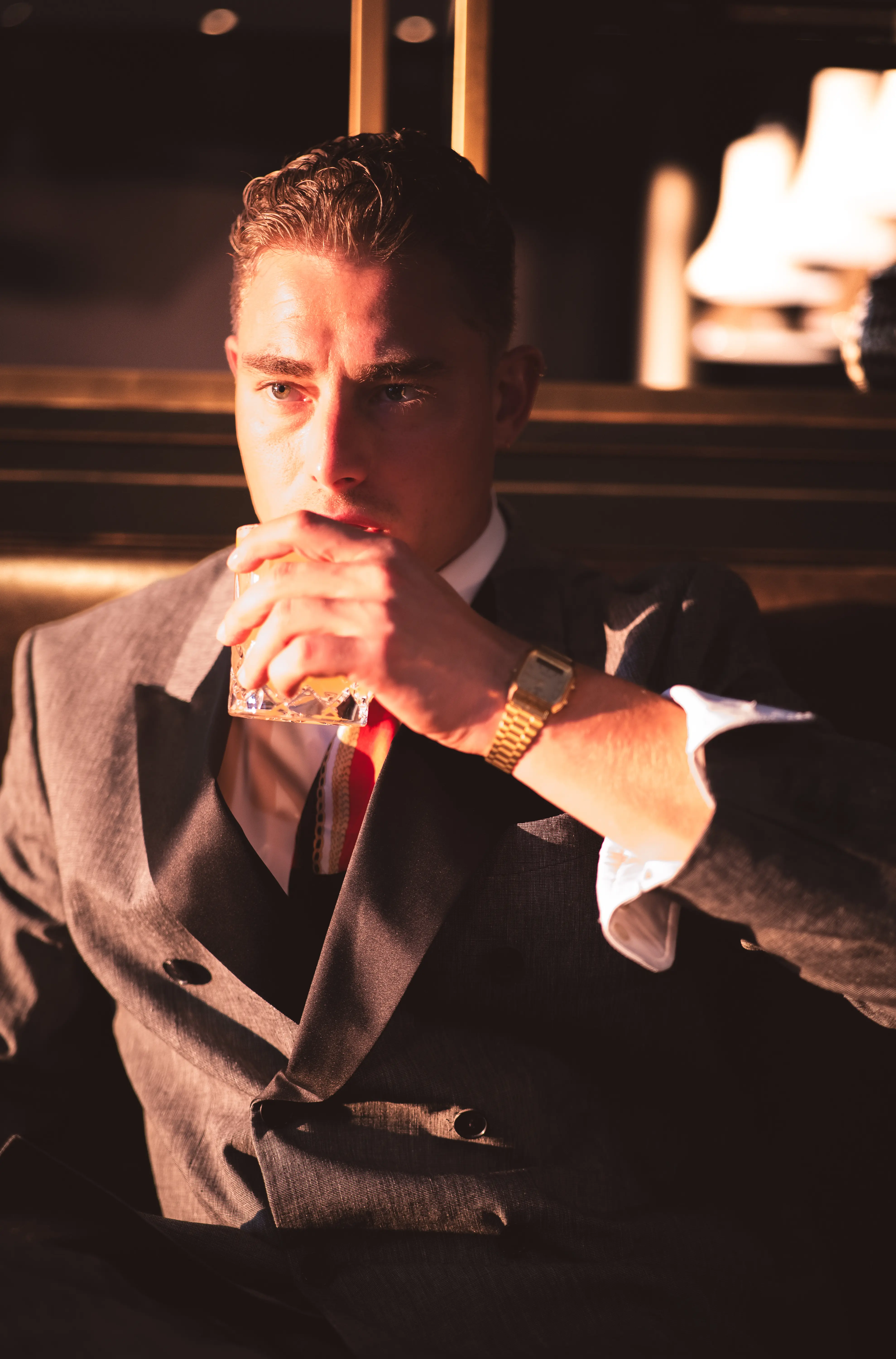 Dramatisches Portrait eines eleganten Mannes im Anzug mit Whiskyglas und Goldarmbanduhr — MarketRamp professionelle Fotografie