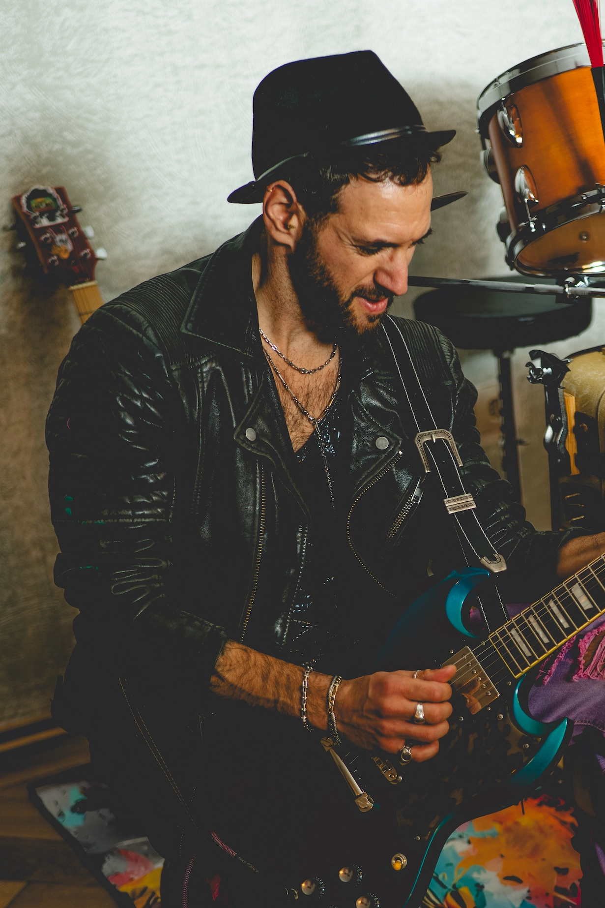 Portrait eines bärtigen Musikers in Lederjacke und Fedora-Hut beim Gitarrespielen — MarketRamp professionelle Fotografie