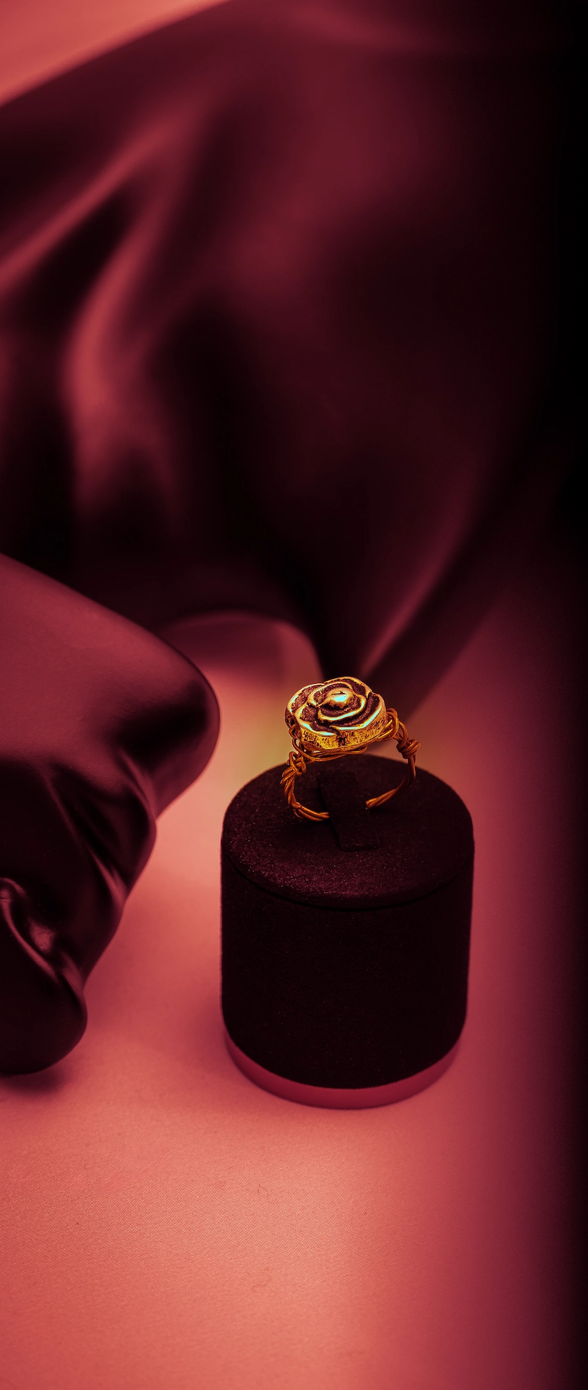 Produktfotografie eines goldenen Rosenrings auf Samtständer mit warmem rosa Licht — MarketRamp Produktfotografie
